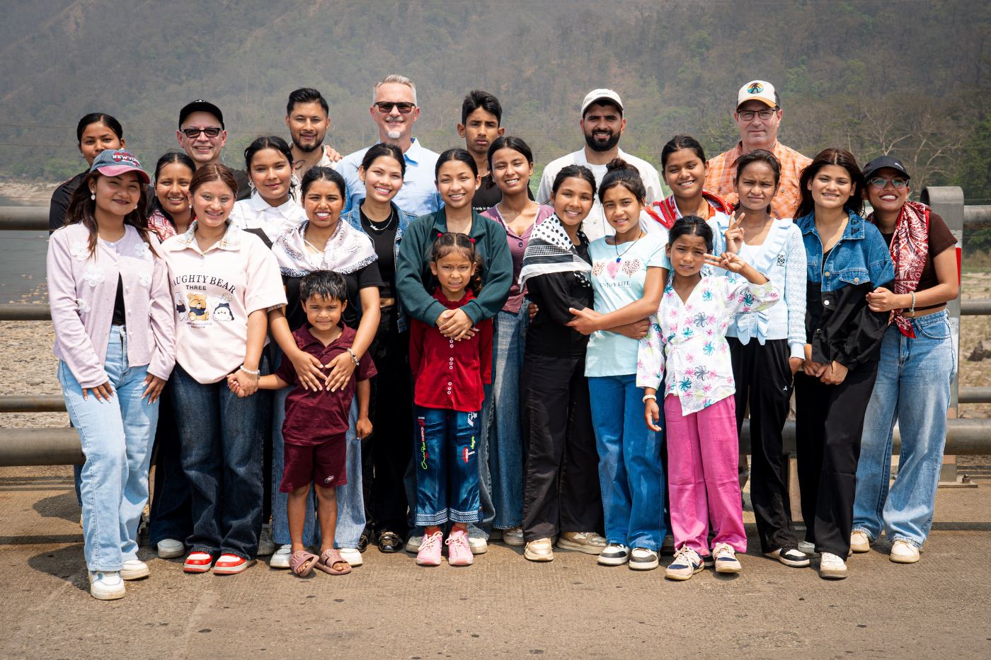 The Hearts for Nepal family — girls, young women, and team together on a bridge in Nepal